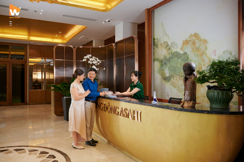 Nhân viên lễ tân Phương Đông Asashi tươi cười chào đón khách hàng đang làm thủ tục check-in.