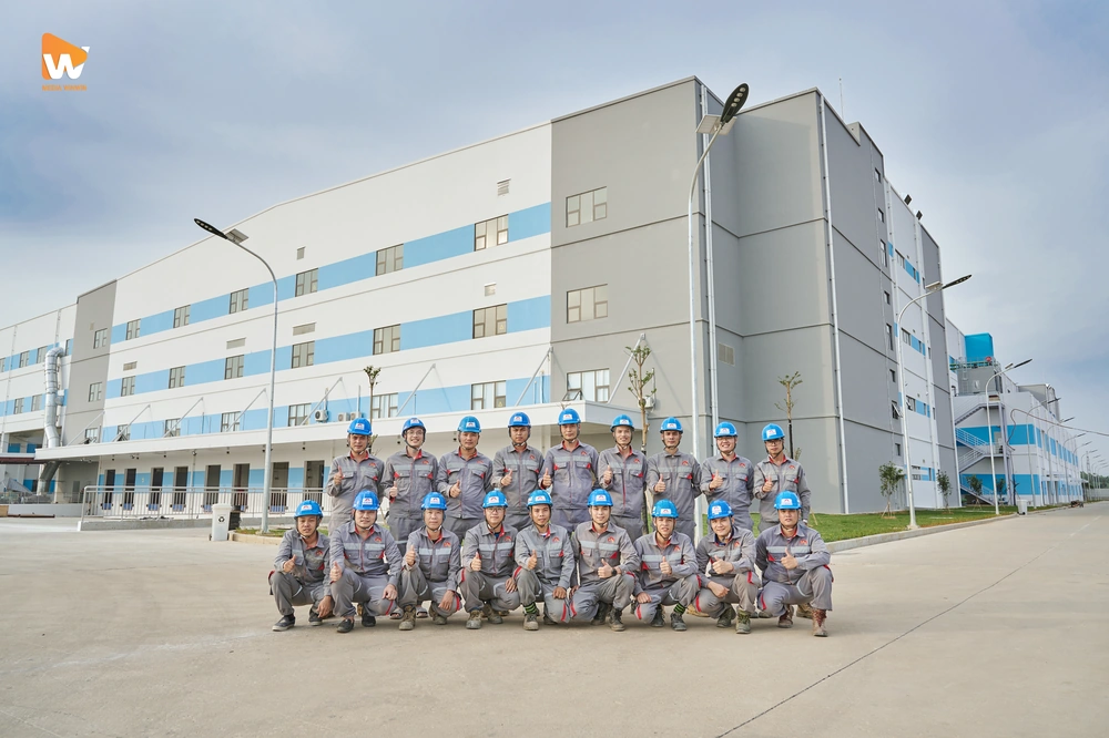 Tập thể nhân viên tươi cười trước nhà máy