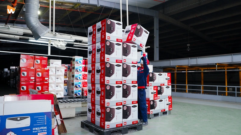 Các kệ hàng cao chất đầy sản phẩm, xe nâng đang hoạt động