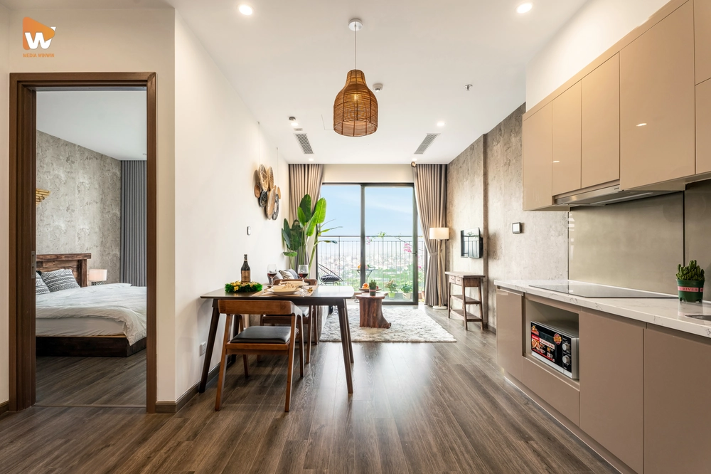 Ảnh chụp chuyên nghiệp không gian bếp và bàn ăn tại homestay Ocean Park, thể hiện sự tiện nghi, hiện đại và góc nhìn ra ban công xanh mát.